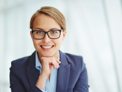 Young businesswoman in eyeglasses looking at camera with toothy smile
